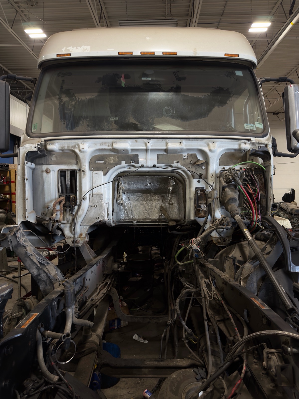 Truck cab with front cap off exposing the electrical wiring during diagnostic at the Planet Truck Brampton shop